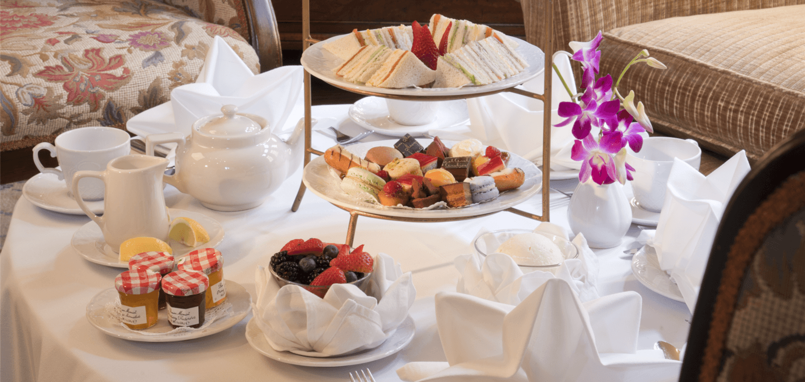 A table set with a tea service, pastries, and fruit.
