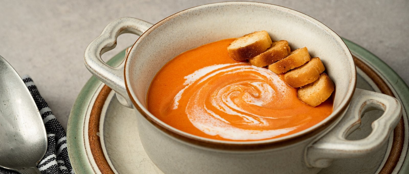 a bowl of tomato soup with bread and cream